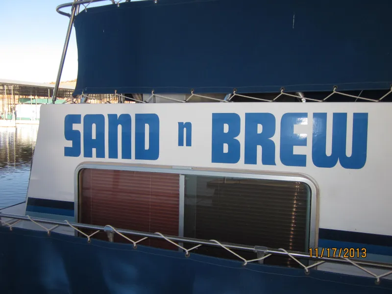 Slide: The Image of 1976 Harbor Master houseboat named "Sand n Brew" docked at a marina. - 8