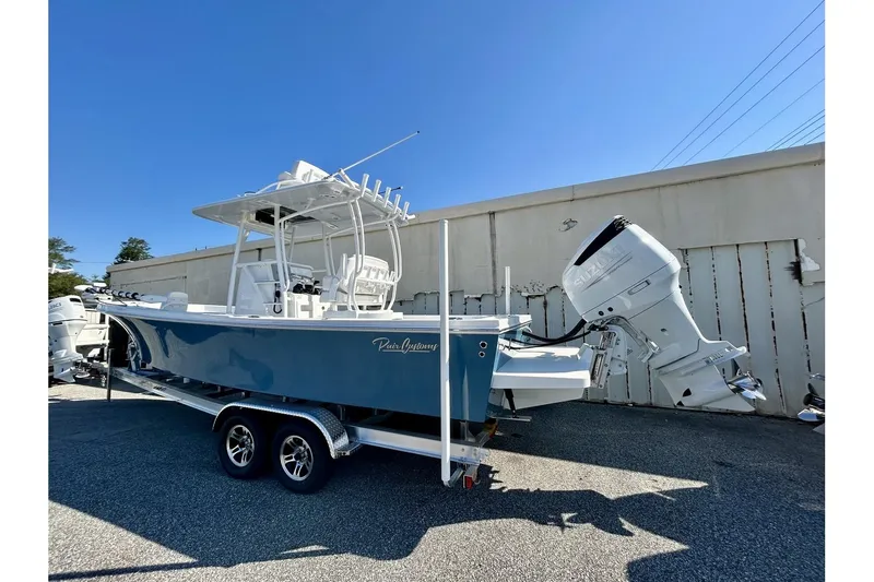 Slide: The Image of 2025 Pair Customs 24 Center Console MV boat on trailer, blue hull, outboard motor. - 2