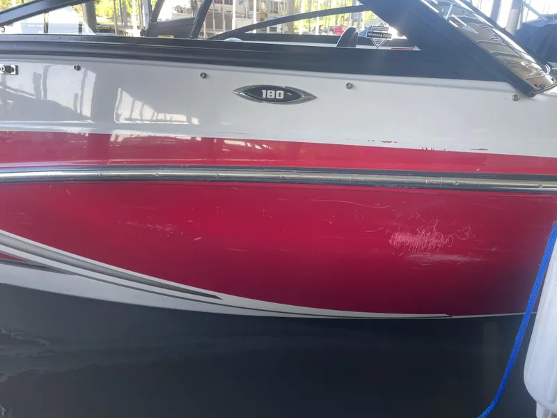 Slide: The Image of 2020 Glastron GT 180 boat with red and white exterior, docked in water. - 1