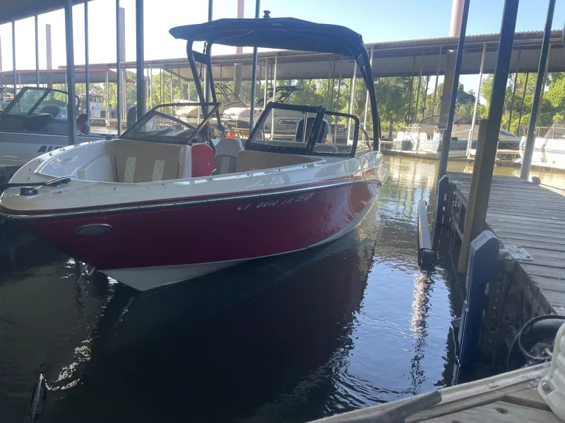 Slide: The Image of 2020 Glastron GT 180 boat docked in marina, red and white exterior. - 2