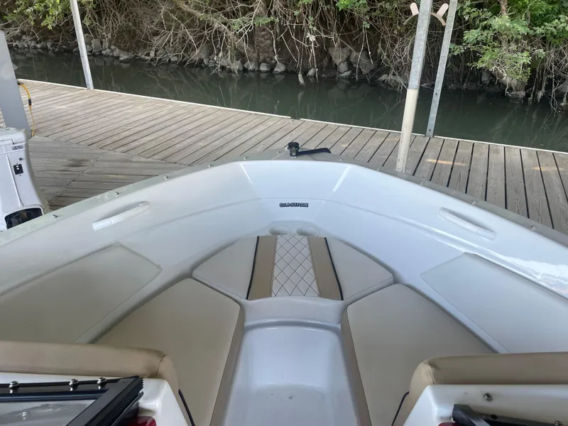 Slide: The Image of 2020 Glastron GT 180 boat interior at dock, featuring beige seating and white hull. - 6
