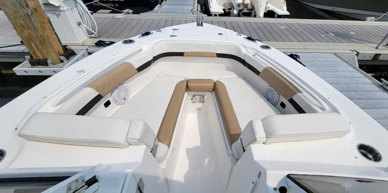 Slide: The Image of 2019 Edgewater 230 CX boat interior with white and tan seating at dock. - 10