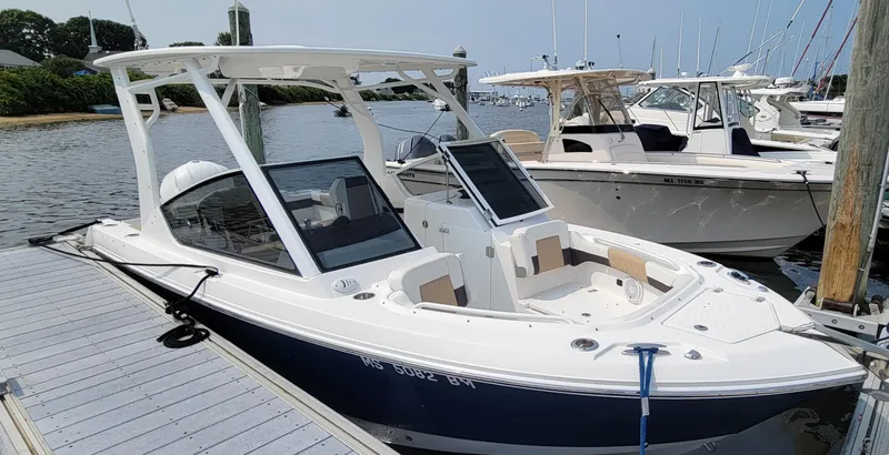 Slide: The Image of 2019 Edgewater 230 CX boat docked at marina, featuring sleek design and spacious seating. - 2