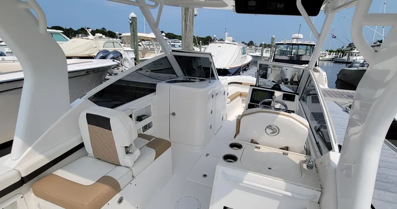 Slide: The Image of 2019 Edgewater 230 CX boat interior at marina, featuring seating and control panel. - 3