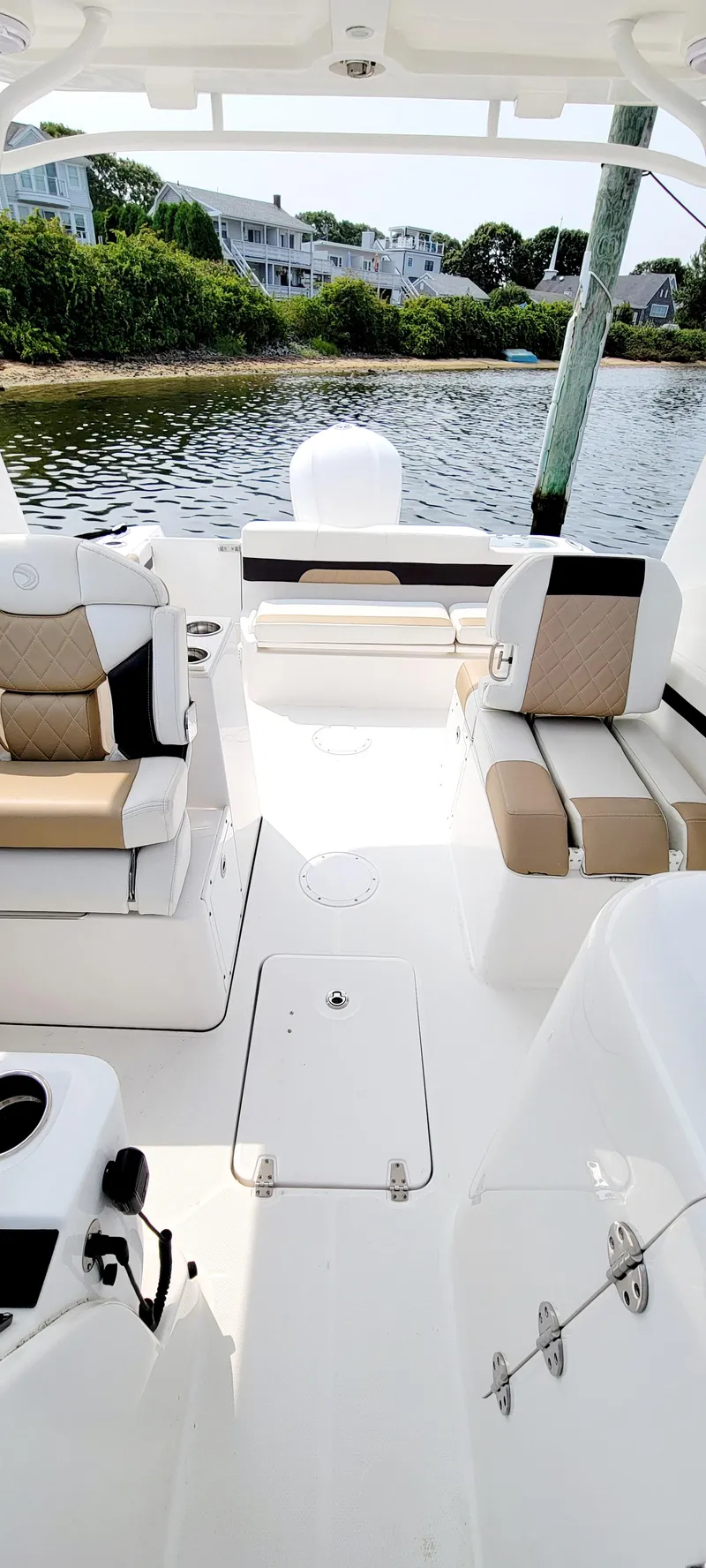 Slide: The Image of 2019 Edgewater 230 CX boat interior with seating, near waterfront homes. - 4