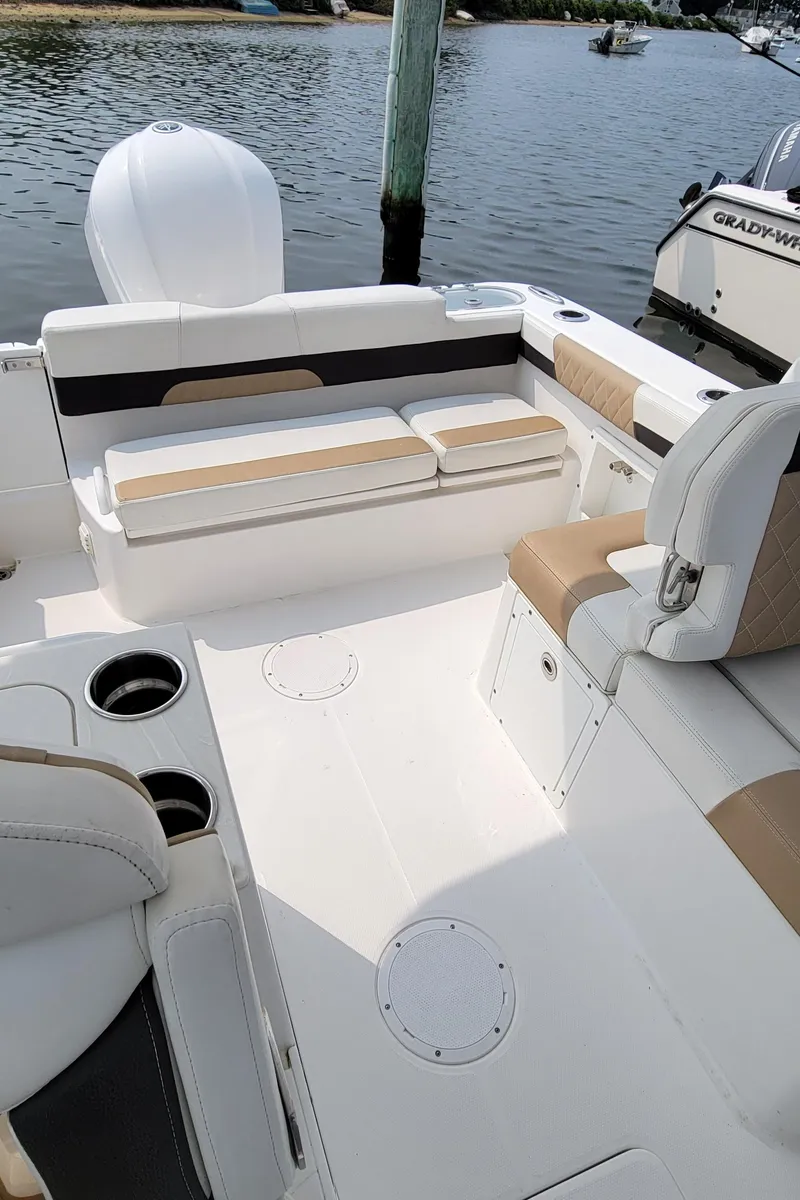 Slide: The Image of 2019 Edgewater 230 CX boat interior with seating and cup holders by the water. - 9