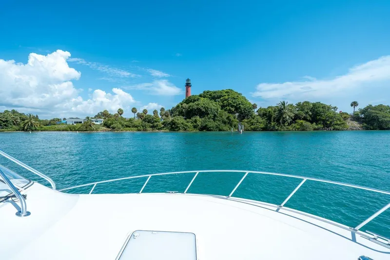Slide: The Image of Cabo 40 Express 2020 yacht cruising near lush island with lighthouse under blue sky. - 30