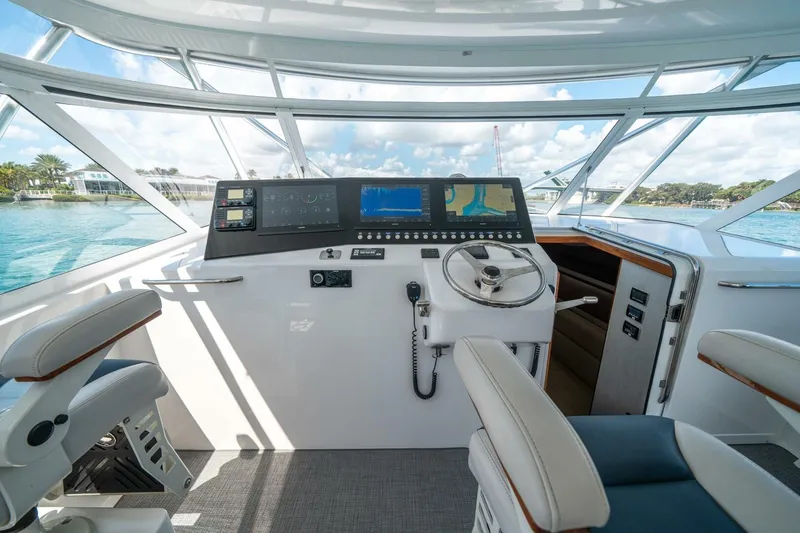 Slide: The Image of 2020 Cabo 40 Express yacht helm with modern navigation equipment and panoramic windows. - 48