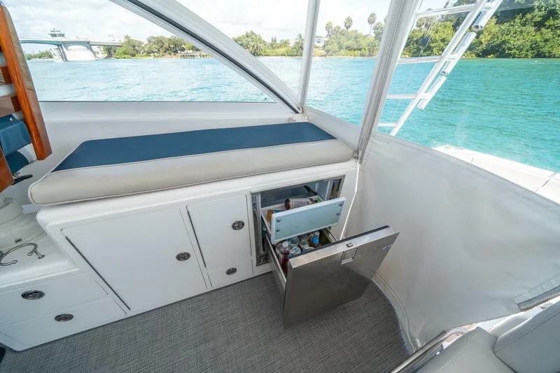 Slide: The Image of 2020 Cabo 40 Express yacht interior with open mini-fridge, overlooking serene water view. - 58