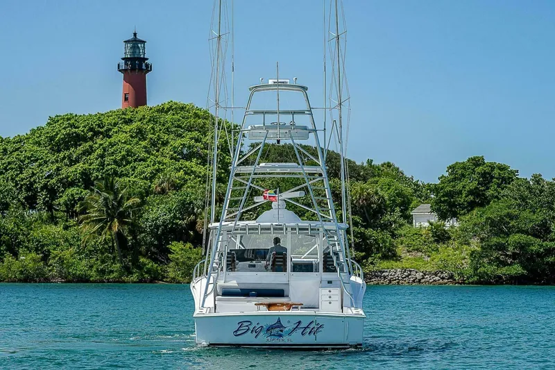 Slide: The Image of Cabo 40 Express 2020 yacht near lush island with lighthouse in background. - 62