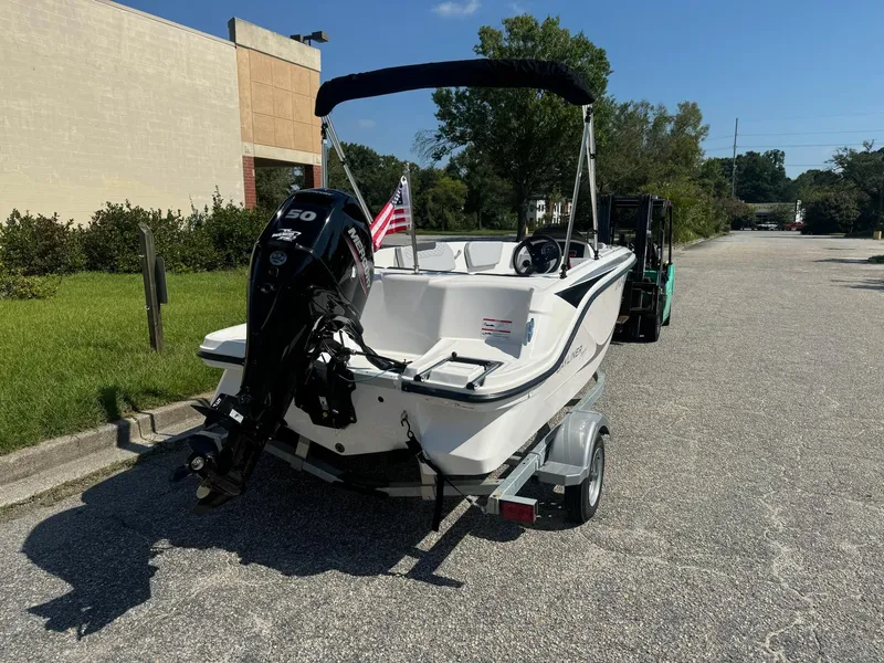 Slide: The Image of 2024 Bayliner Element M15 boat on trailer, parked outdoors with American flag. - 8