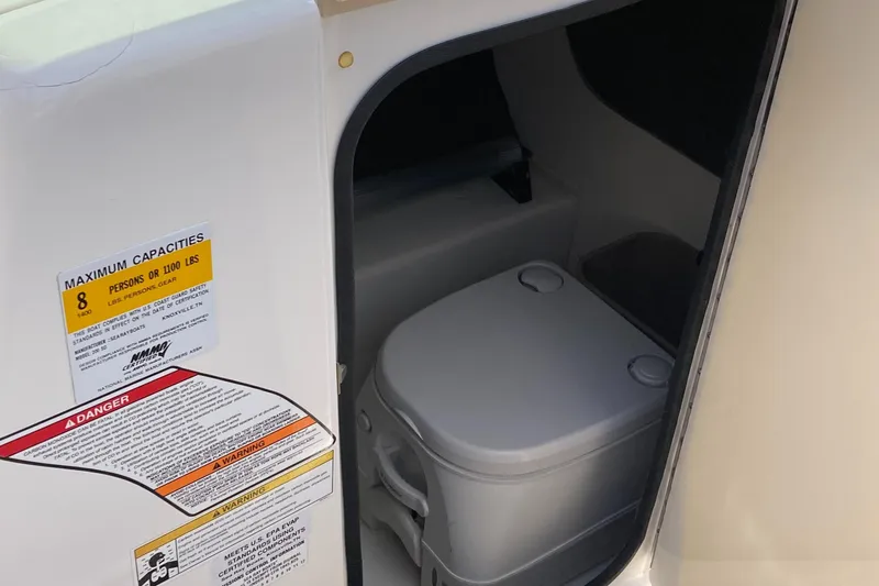 Slide: The Image of 2012 Sea Ray 200 Sundeck boat interior with portable toilet and capacity labels. - 11