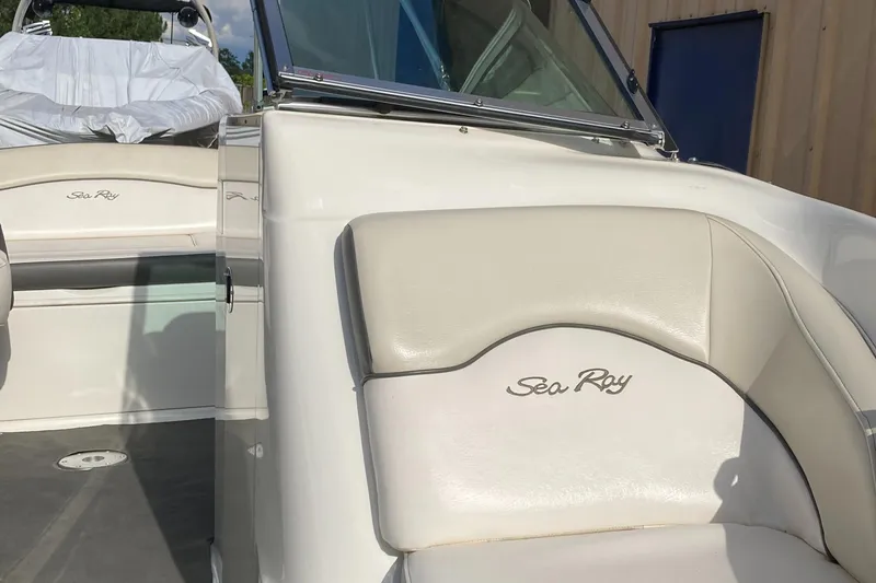 Slide: The Image of 2012 Sea Ray 200 Sundeck boat interior with beige seating and logo. - 9
