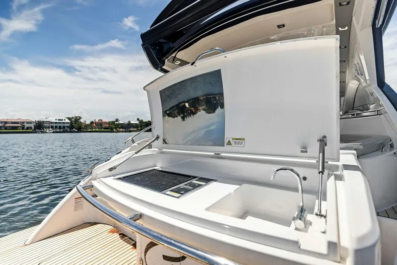 Slide: The Image of 2022 Schaefer 400 Coupe yacht with outdoor kitchen and sink, docked by a scenic waterfront. - 30