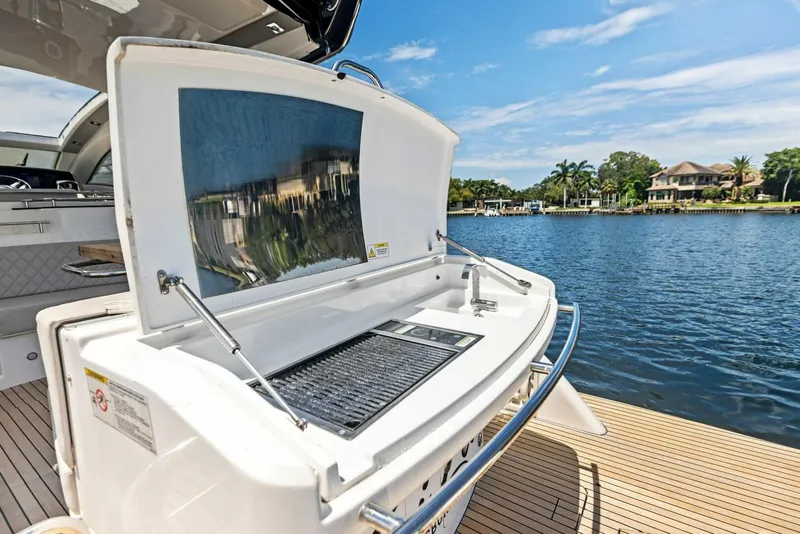 Slide: The Image of Schaefer 400 Coupe 2022 yacht with open grill, docked by a scenic waterfront. - 31