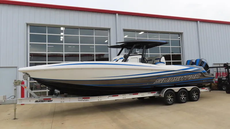 Slide: The Image of 2023 Sunsation 32 CCX boat on trailer outside a garage. - 2