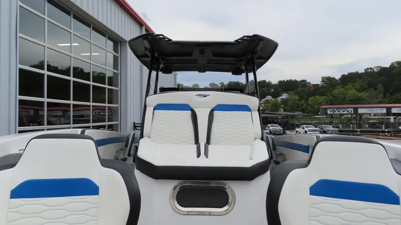 Slide: The Image of 2023 Sunsation 32 CCX boat interior with blue and white seating near a marina. - 24