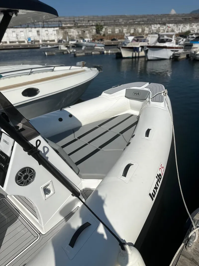 Slide: The Image of Aqvaboats Luxrib 25, 2025 model, docked in a marina with other boats. - 13
