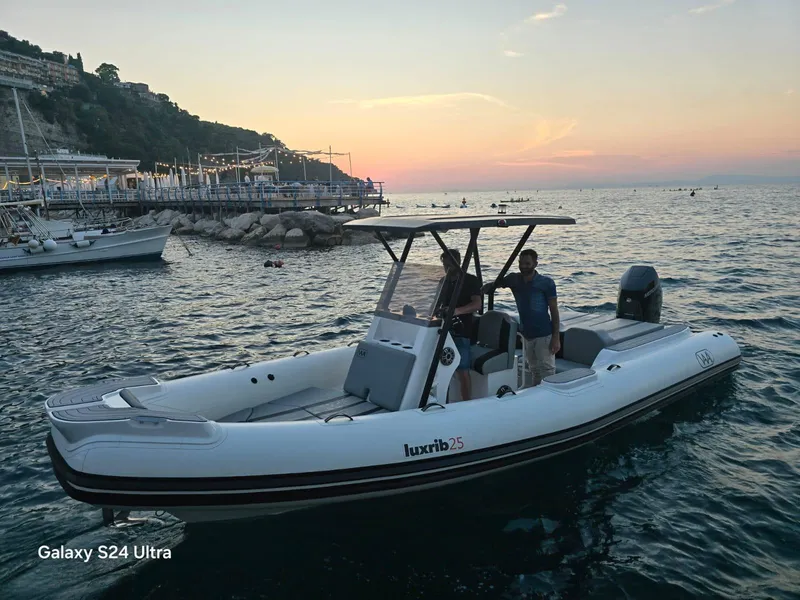 Slide: The Image of Aqvaboats Luxrib 25, 2025 model, cruising at sunset near a scenic coastline. - 15