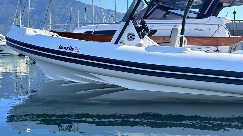 Slide: The Image of Aqvaboats Luxrib 25, 2025 model, docked in a serene marina setting. - 3