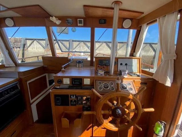Slide: The Image of 1973 Grand Banks 42 Classic helm with wooden wheel, navigation instruments, and panoramic windows. - 18
