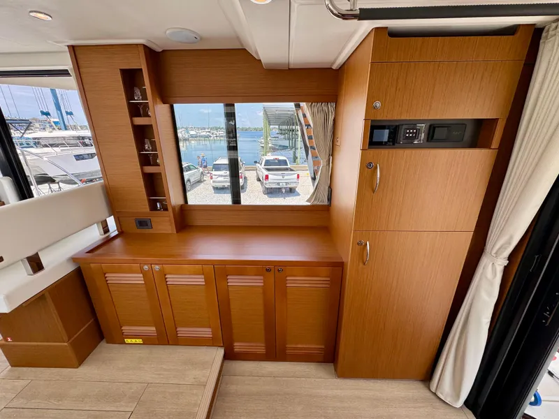 Slide: The Image of 2025 Beneteau Swift Trawler 41 Fly interior with wood cabinetry and marina view. - 14