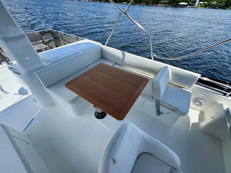 Slide: The Image of 2025 Beneteau Swift Trawler 41 Fly deck with seating and wooden table, overlooking water. - 23