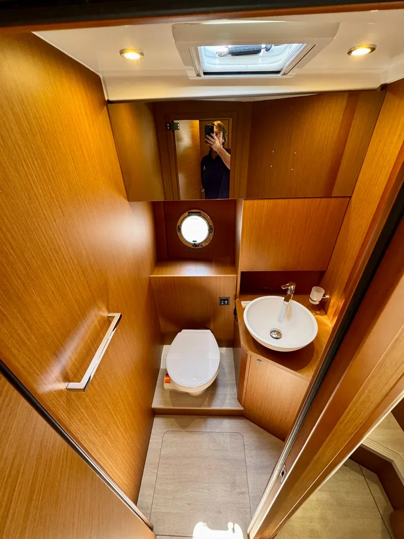 Slide: The Image of 2025 Beneteau Swift Trawler 41 Fly bathroom with wood finish, skylight, and porthole window. - 7