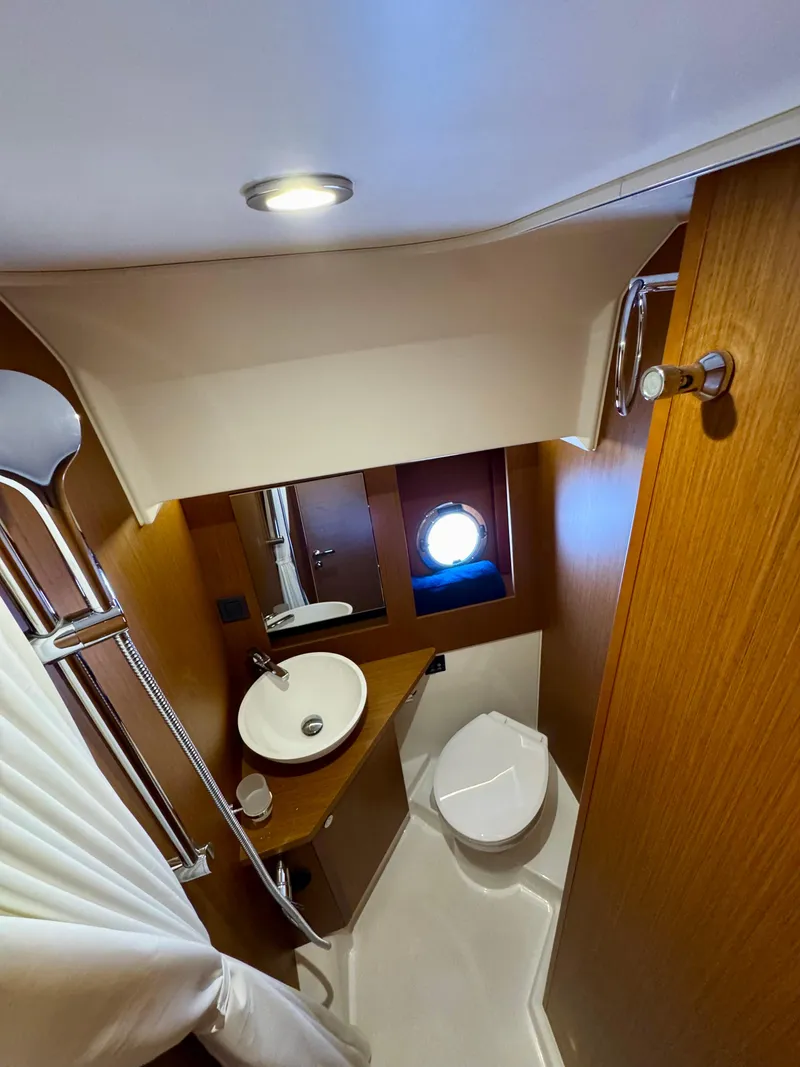 Slide: The Image of 2025 Beneteau Swift Trawler 41 Fly bathroom with modern fixtures and porthole window. - 9