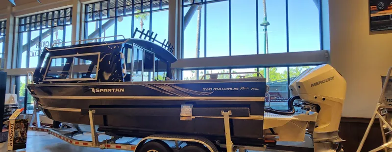 Slide: The Image of 2024 Spartan 260 Maximus Pro XL boat displayed indoors on a trailer. - 0