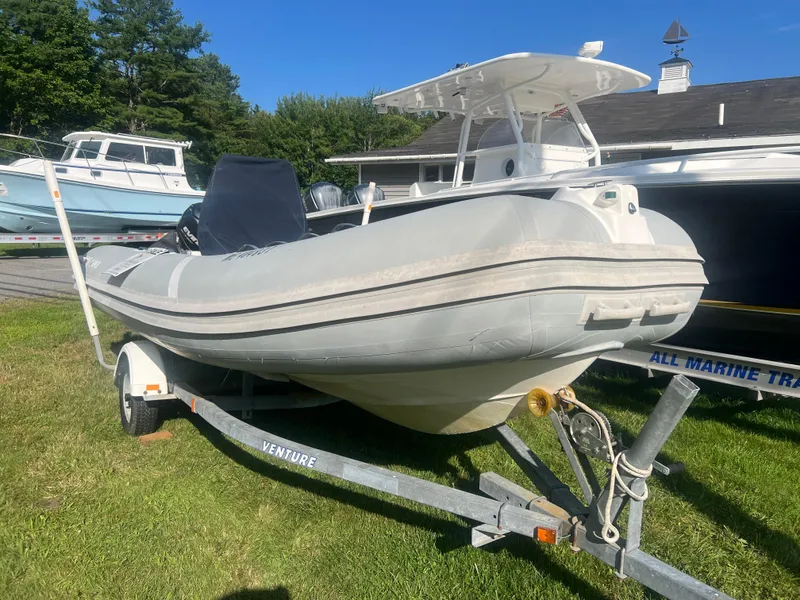 Slide: The Image of 2005 Apex Marine 17 boat on trailer, parked on grass, with other boats in background. - 7