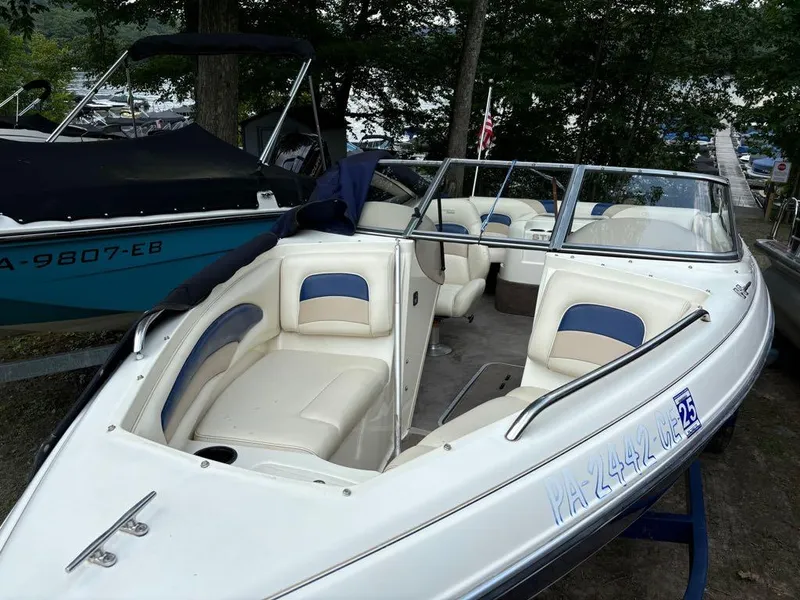 Slide: The Image of 1999 Stingray 190RS boat with white and blue interior, docked near trees. - 10