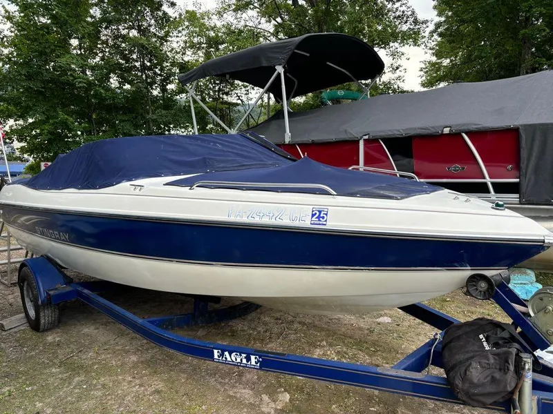 Slide: The Image of 1999 Stingray 190RS boat on trailer, covered, parked outdoors. - 13