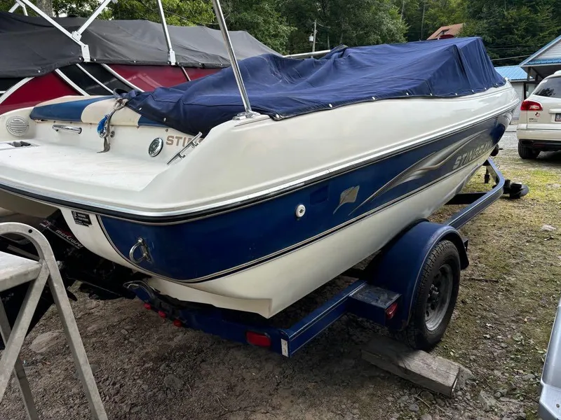 Slide: The Image of 1999 Stingray 190RS boat with blue cover on trailer, parked outdoors. - 16
