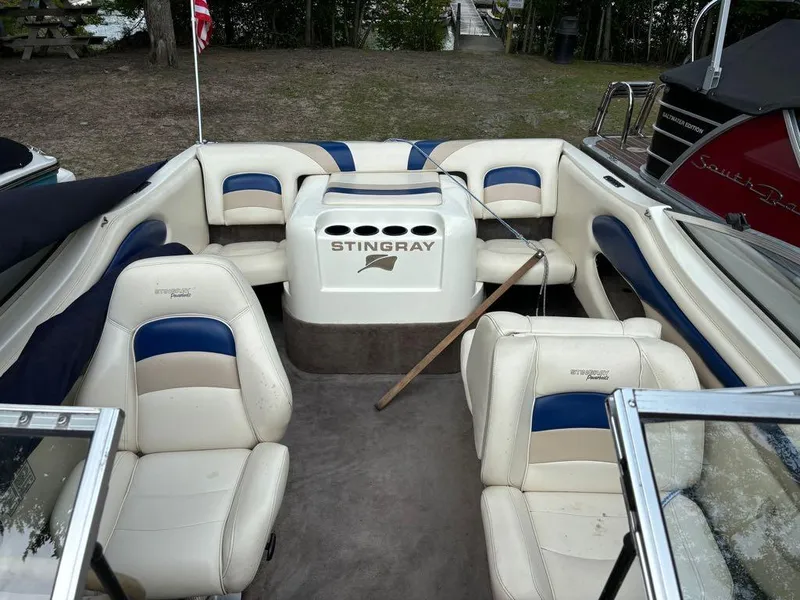 Slide: The Image of 1999 Stingray 190RS boat interior with white and blue seating, docked near a wooded area. - 27