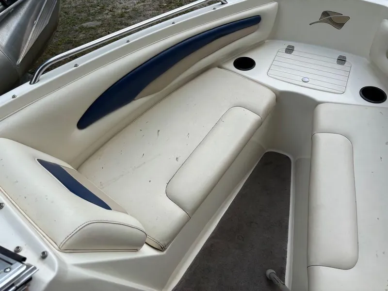 Slide: The Image of 1999 Stingray 190RS boat interior with white and blue seating, cup holders, and storage. - 29