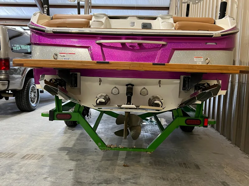 Slide: The Image of 2016 MasterCraft X26 boat with vibrant pink and silver hull on a green trailer. - 10