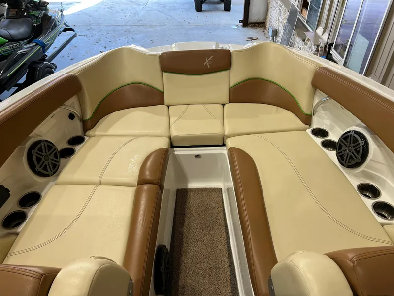 Slide: The Image of 2016 MasterCraft X26 boat interior with tan and brown seating, cup holders, and speakers. - 22