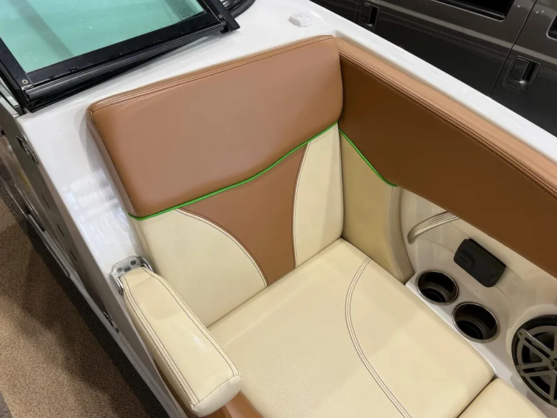 Slide: The Image of 2016 MasterCraft X26 boat interior with tan and cream seating, green accents, and cup holders. - 26
