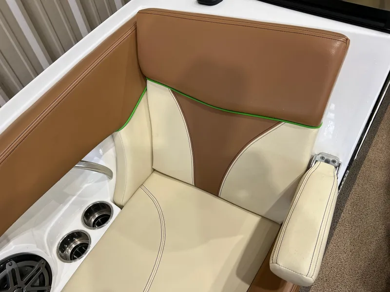 Slide: The Image of 2016 MasterCraft X26 boat seat with tan and cream upholstery, green accents, and cup holders. - 27