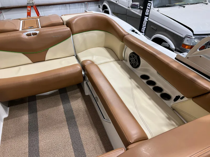 Slide: The Image of 2016 MasterCraft X26 boat interior with tan and cream seating, cup holders, and speaker. - 29