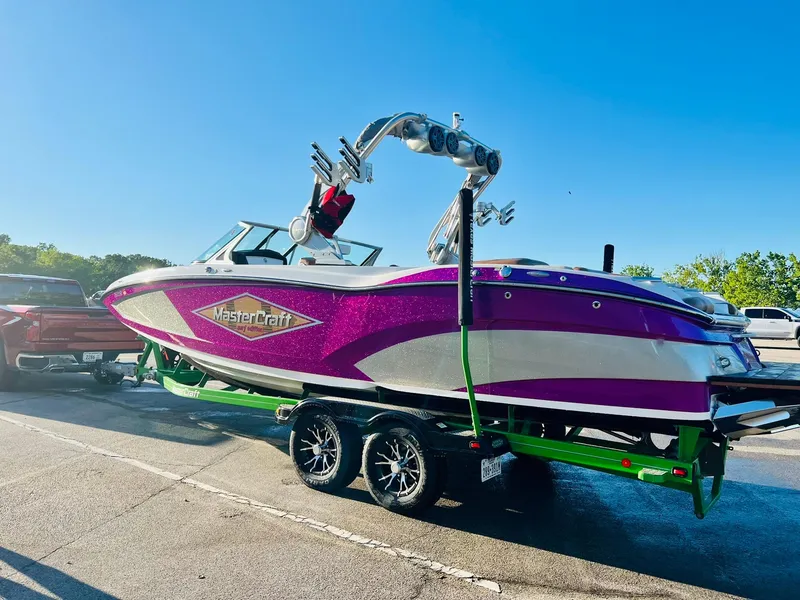 Slide: The Image of 2016 MasterCraft X26 boat with vibrant purple and white design on a trailer. - 3