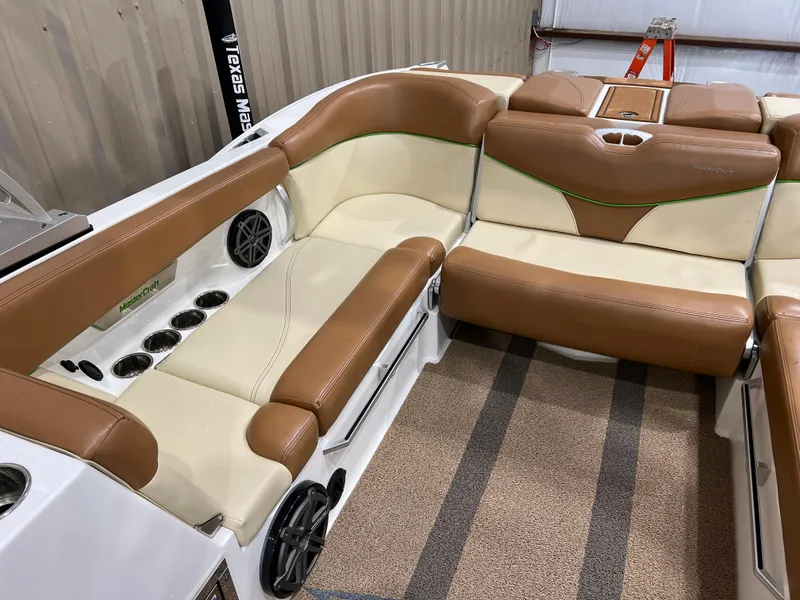 Slide: The Image of 2016 MasterCraft X26 boat interior with tan and cream seating, cup holders, and speakers. - 30