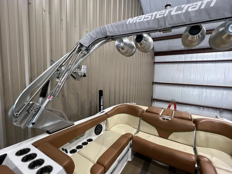Slide: The Image of 2016 MasterCraft X26 boat interior with beige and brown seating, metal frame, and speakers. - 31