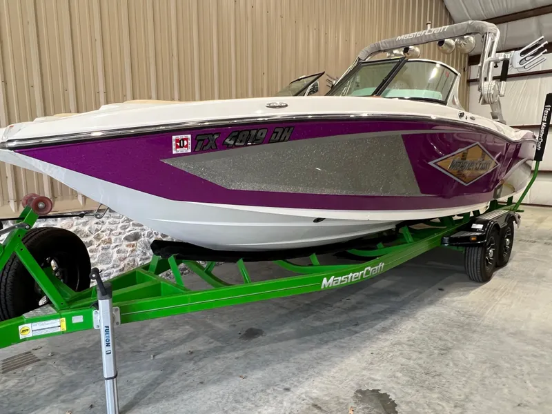 Slide: The Image of 2016 MasterCraft X26 boat with purple and silver design on a green trailer. - 4