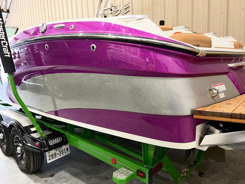 Slide: The Image of 2016 MasterCraft X26 boat with vibrant purple and silver exterior on a green trailer. - 42