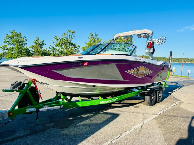 Slide: The Image of 2016 MasterCraft X26 boat on a green trailer by a lake. - 43