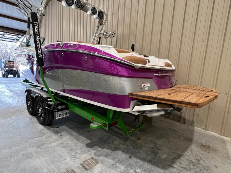 Slide: The Image of 2016 MasterCraft X26 boat with vibrant purple and silver design in a storage facility. - 5