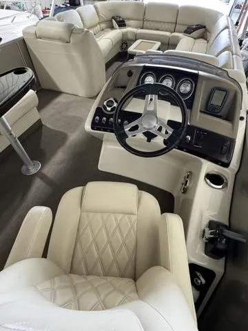 Slide: The Image of 2013 Bennington 2575 R boat interior with beige leather seating and modern dashboard. - 13