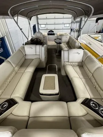 Slide: The Image of 2013 Bennington 2575 R pontoon boat with spacious seating and canopy in a garage. - 19